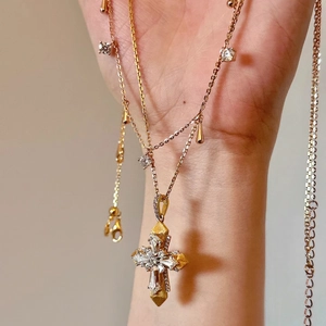 Macro shot of two-tone gold cross pendant featuring Italian brushed texture and crystals