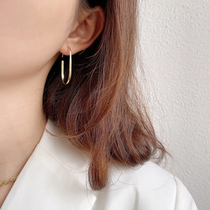 Close-up of gold U-shaped 925 sterling silver earrings worn by a model in soft light