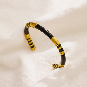 Detail showing the gold and black striped enamel texture on the stainless steel bangle