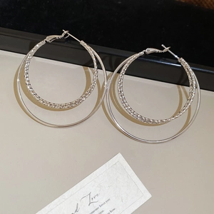Macro detail of silver double hoop earrings with faceted texture and polished mirror finish