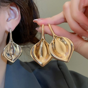 Dettaglio macro di orecchini a giglio calla in metallo con finiture oro e argento