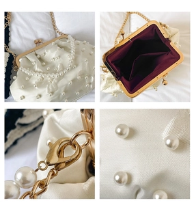 Detail view of cream satin shell bag with pearl beads, gold hardware and red lining