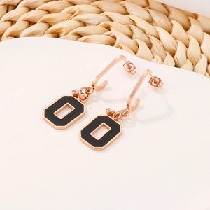Detail of rose gold geometric drop earrings with black enamel and sparkling zircon inlay