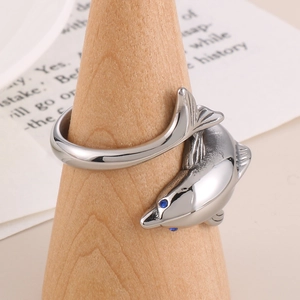 Polished stainless steel dolphin ring with blue eyes on a wooden display stand