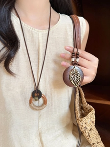 Detailed view of Bohemian wooden bead necklace with a hollow leaf metal pendant