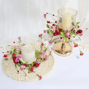 Detail of candle ring featuring red berries and pink heart ornaments on a table