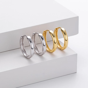 Close-up of gold and silver S925 sterling silver hoop earrings with metal hallmark detail