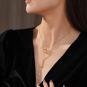 Detail of a golden Y-shaped long heart pendant necklace worn on black velvet fabric