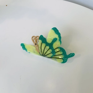 Detail of butterfly hair claw clip with green acetate wings and glitter embellishments