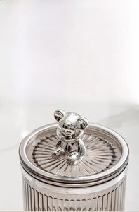 Detail of dustproof lid featuring a silver chrome bear on a brown striped storage jar
