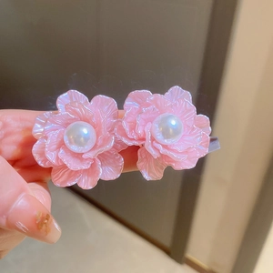 Macro detail of sweet pink flower stud earrings featuring a central faux pearl bead.