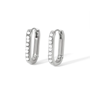 Macro view of silver huggie earrings featuring vertical row of small white pearls