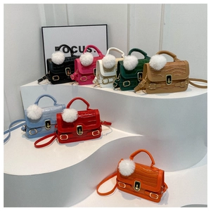 Bunte Handtaschen mit Steinmuster auf weißen Stufen mit plüschigen Anhängern gezeigt