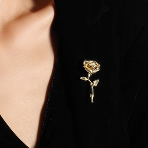 Gold-plated rose flower brooch pinned on a black suit lapel with detailed metal petals