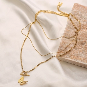 Close-up of golden multi-layer chain necklace with butterfly pendant on pink stone