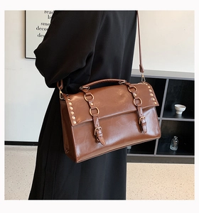 Detail of vintage brown shoulder bag with metal ring buckle and decorative rivets