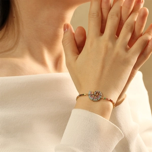 Macro detail of gold spiral nautilus bracelet charm with vibrant multi-color zircons
