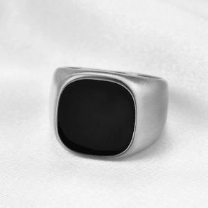 Detail of vintage matte silver signet ring with black enamel inlay on white silk