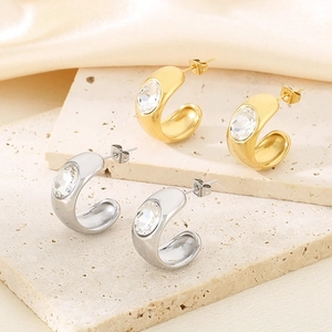 Detail of C-shaped stainless steel stud earrings with crystal on travertine stone