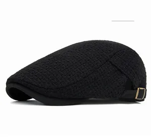 Detailed view of black knitted waffle texture and bronze metal buckle on newsboy cap