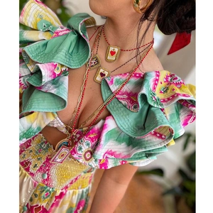 Close-up of layered beaded necklace with heart pendant and gold hoop earrings on model