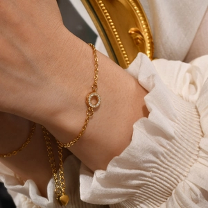 Close-up of 18K gold-plated bracelet with pavé zircon round charm and heart pendant