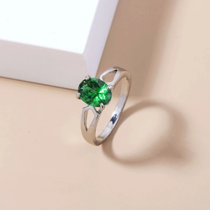 Macro shot of silver ring with oval green gemstone and pavé zircon split band detail
