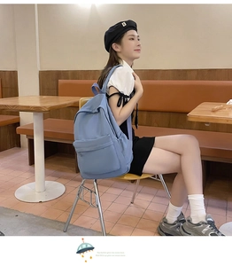 Detail view of a large blue casual nylon backpack worn by a model in a cafe setting