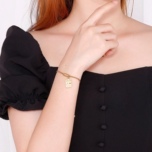 Elegant gold bracelet with rectangular pearl pendant on female model's wrist