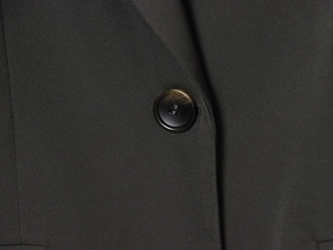 Détail rapproché d'un blazer gris anthracite montrant un bouton en résine marbré élégant