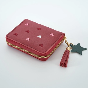 Detail of reddish-brown leather wallet with embroidered hearts and tassel zipper pull