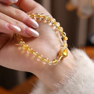 Elegant citrine beaded bracelet with gold heart pendant and coin charm on model wrist