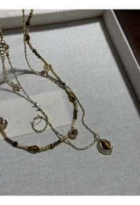 Close-up of vintage gold layered beaded chain necklace with tiger eye stone oval pendant