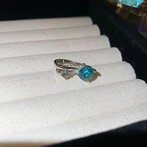 Vue macro d'une bague argentée avec pierre bleue et accents blancs dans son écrin
