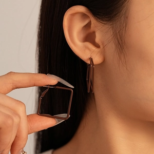 Detail of brown geometric square C-shape earrings with matte finish on model