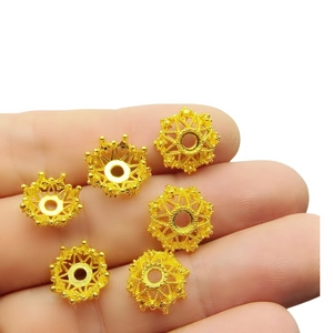 Detailed view of hollow patterned gold alloy bead caps for DIY jewelry making and beading