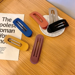 Matte finish long hair clips in multiple colors displayed on a wooden surface