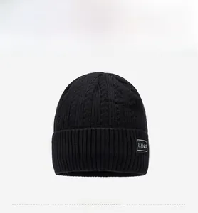 Close-up of black cable knit pattern and brand label on a warm winter beanie hat