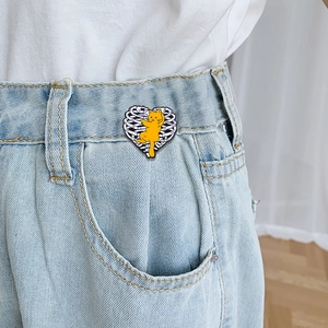 Skeleton heart enamel pin with orange cat on denim, unique gothic style metal badge