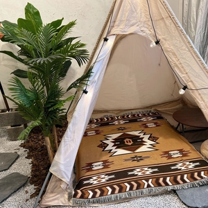 Detail of bohemian geometric woven camping blanket with fringes inside a cozy tent