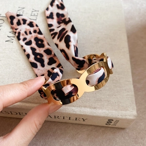 Detail of gold chain bracelet with leopard print silk scarf intertwined on a book