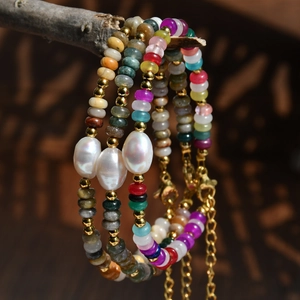 Détail de perles de pierre colorées et perles d'eau douce sur bracelets avec chaînes dorées