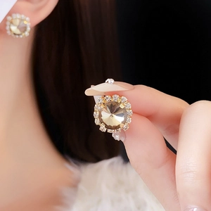 Close-up of gold halo stud earrings featuring a champagne stone and crystal border
