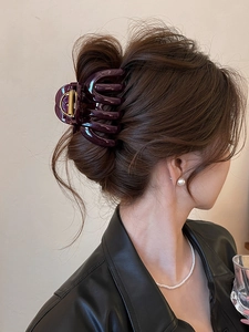 Detail shot of a dark purple acrylic hair claw clip used for an elegant updo hairstyle