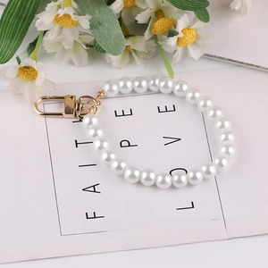 Detail of white glass pearl phone chain with golden lobster clasp on floral card background
