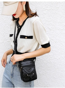 Detail of black faux leather mini crossbody phone bag with multi-zipper and woven texture