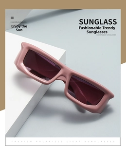 Close-up of pink thick frame sunglasses with dark purple lenses on geometric props