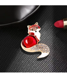 Close-up of a vintage golden fox brooch with red glass belly and sparkling rhinestones