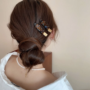 Detail of tortoise shell acrylic hair clips with rhinestones on a side bun hairstyle
