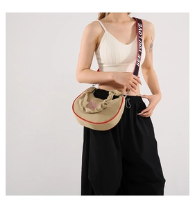 Détail d'un sac bandoulière beige avec broderie papillon et sangle rayée